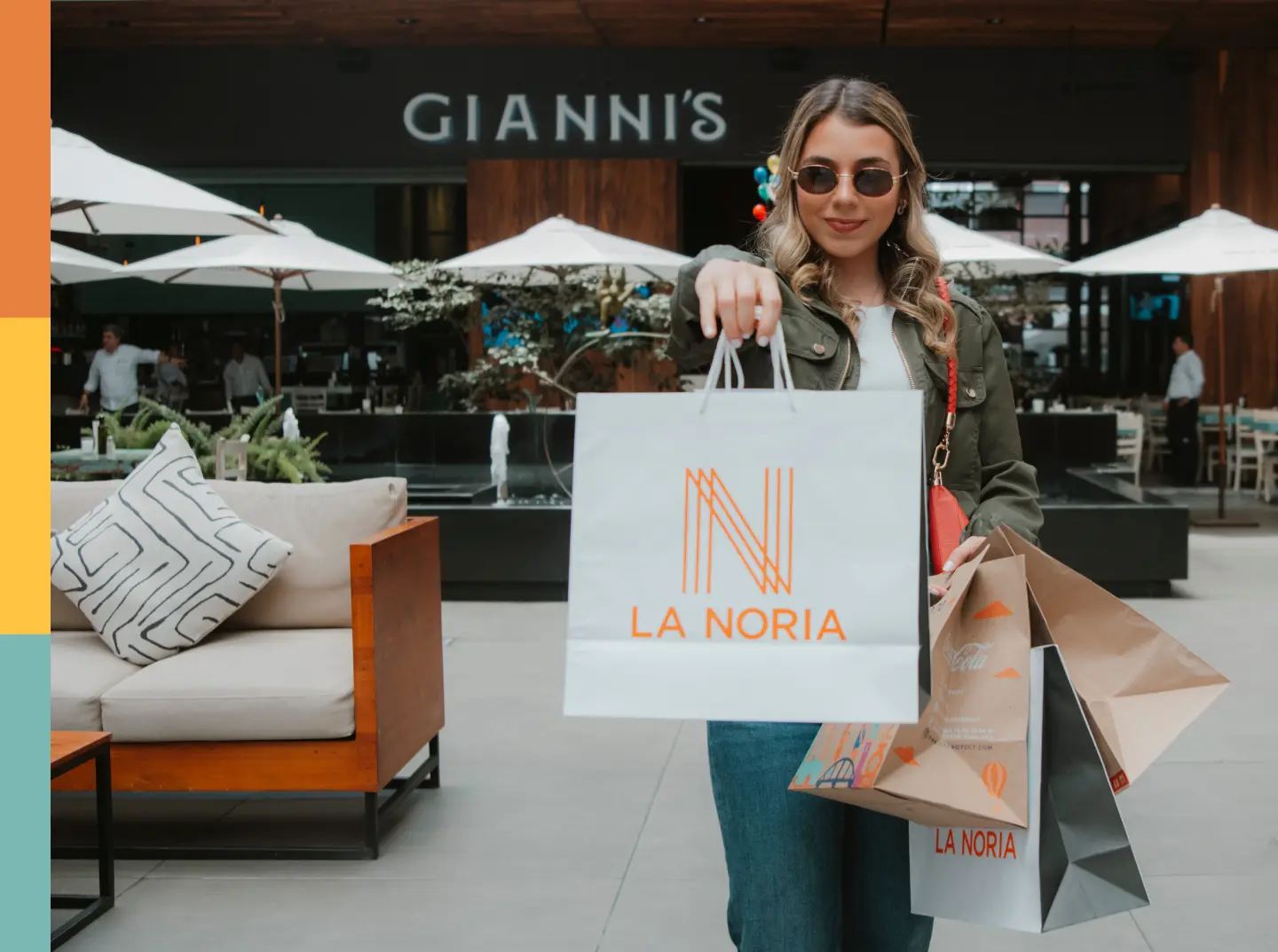 Visitante en La Noria con bolsas de compras frente a Gianni’s